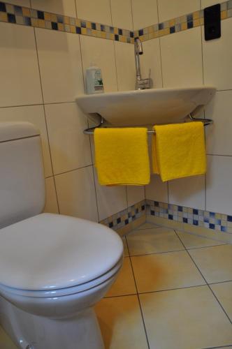 a bathroom with a toilet and a sink and yellow towels at Ferienwohnung am Waldrand in Obernhain