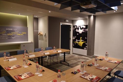 a conference room with wooden tables and chairs and a screen at Ibis Sfax in Sfax