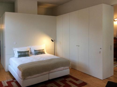 a white bedroom with a bed and white cabinets at Villa Lóios by Casa do Conto in Porto
