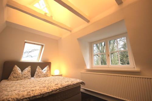 ein Schlafzimmer mit einem Bett und zwei Fenstern in der Unterkunft Nordheidehaus in Asendorf