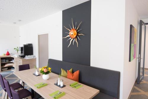 a dining room with a table and a sun sculpture on the wall at Hotelmyhome in Hornberg
