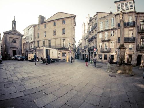 a woman walking down a city street with buildings at Albergue The Last Stamp in Santiago de Compostela