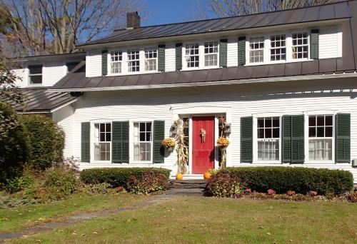 a white house with green shutters and a red door at Artful Lodging & Retreats in Montpelier