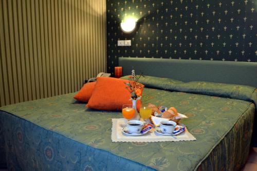 Una cama con una bandeja de comida y bebidas. en Hotel Pineta, en Falcade