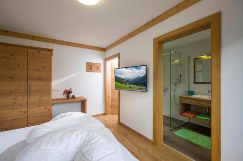 a bedroom with a bathroom with a tv on the wall at Bergsonne in Tux