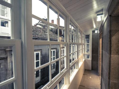 an empty hallway of an apartment building with windows at Albergue The Last Stamp in Santiago de Compostela
