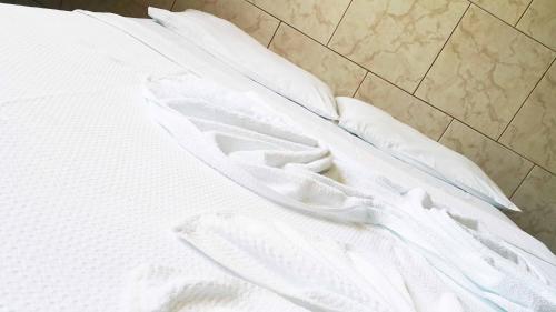 a white bed with white sheets and pillows at Yves Hotel in Porto Velho