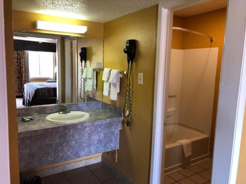 een badkamer met een wastafel, een spiegel en een bad bij Lone Star Inn in Lubbock