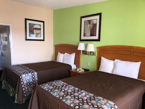 two beds in a hotel room with green walls at Lone Star Inn in Lubbock
