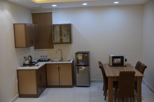 a kitchen with a wooden table and a refrigerator at Shatha Abha Furnished Units in Abha