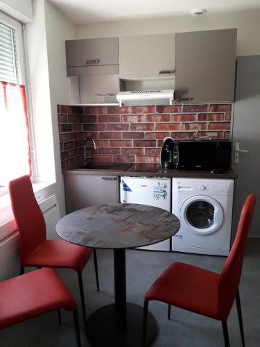 a kitchen with a table and chairs and a washing machine at Residence Miranto in Châteauroux