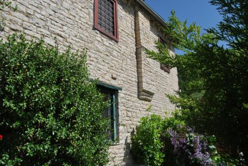 a brick building with a window and some bushes at Tritoxo Guesthouse in Koukouli