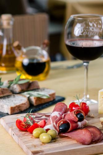 a cutting board with meat and a glass of wine at Villa Royal Apartments in Tivat