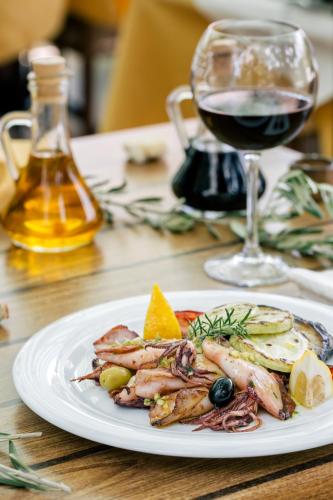 a plate of shrimp and eggs with a glass of wine at Villa Royal Apartments in Tivat