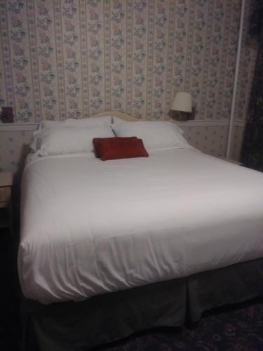 a white bed with a red pillow on top of it at Thayers Inn in Littleton
