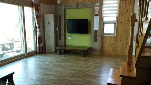 um quarto com uma televisão numa parede com um banco em Sunmoon Pension em Yeosu