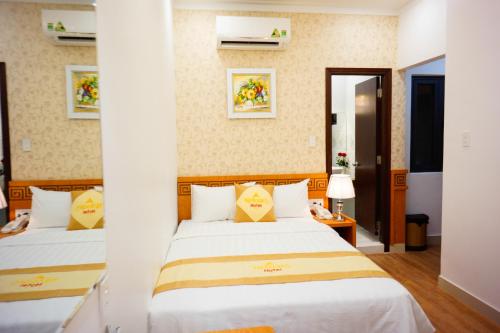 two beds in a hotel room with white sheets at NỮ HOÀNG HOTEL in Phan Rang