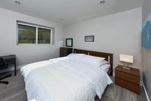 a bedroom with a white bed and a desk and a window at The Chateau in Burnaby