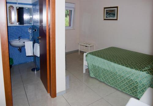 a bathroom with a bed and a sink in a room at Hotel Cristallo in Lerici