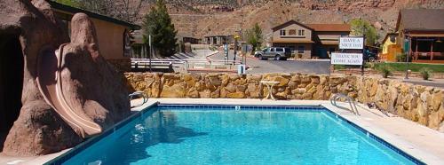 a large blue swimming pool with a rock wall at Zion Park Motel in Springdale