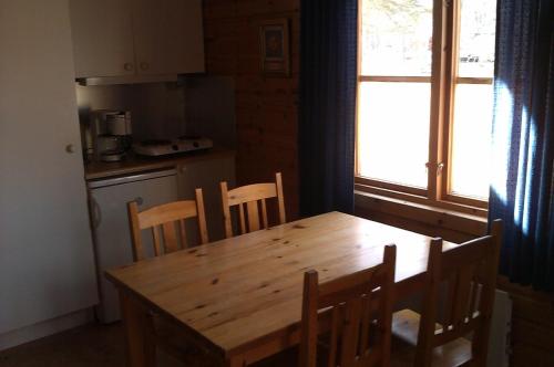 una mesa de madera y sillas en una cocina con ventana en Wassbacken Vandrarhem, en Töreboda