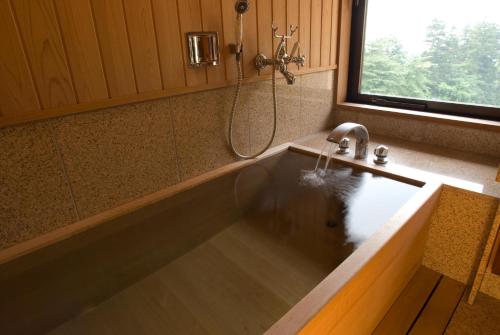 a bathroom with a bath tub with a sink at Oyado Tamaki in Shibukawa