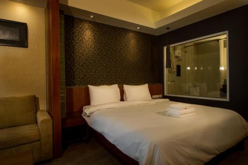 a bedroom with a bed with a chair and a mirror at Inn Residence Serviced Suites - SHA Extra Plus in Jomtien Beach