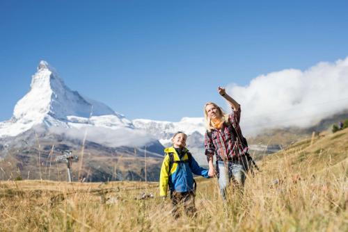two people standing in a field with a mountain in the background at Hotel Butterfly, BW Signature Collection in Zermatt