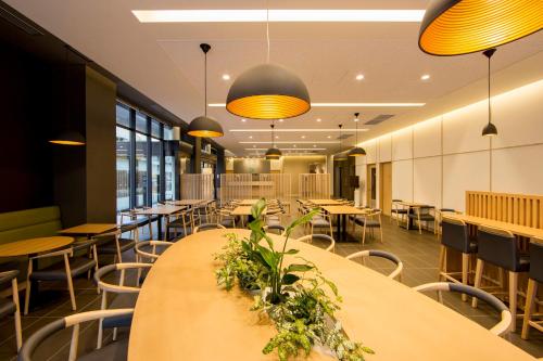 a restaurant with tables and chairs and yellow lights at Karaksa Hotel Osaka Namba in Osaka