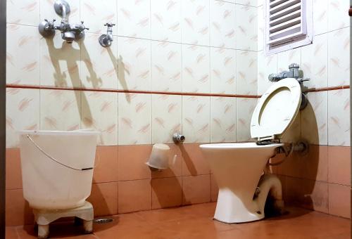 a bathroom with a toilet and a toilet paper dispenser at Hotel Midtown in Haridwār