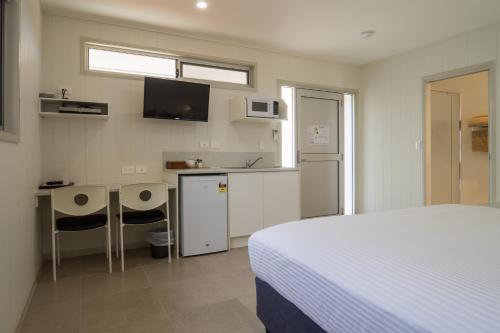 Un dormitorio con una cama y un escritorio y una cocina. en Cooper's Country Lodge, en Eromanga