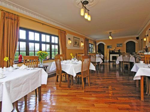 19th Green Guesthouse في كيلارني: مطعم بطاولات وكراسي مع طاولة قماش بيضاء