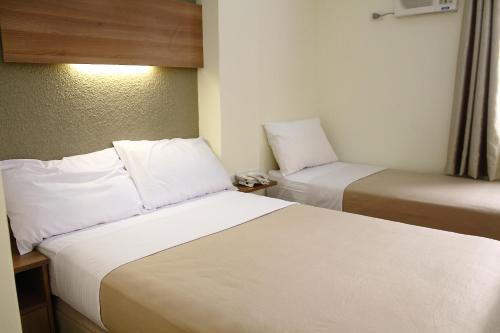 een hotelkamer met 2 bedden met witte lakens bij The Center Suites in Cebu City