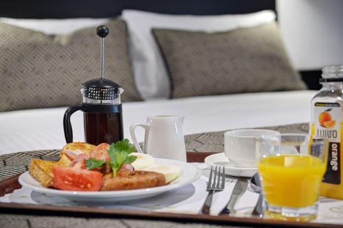 a breakfast table with a plate of food and orange juice at CBD Motor Inn in Coffs Harbour