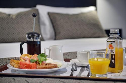 a table with a plate of food and orange juice at CBD Motor Inn in Coffs Harbour