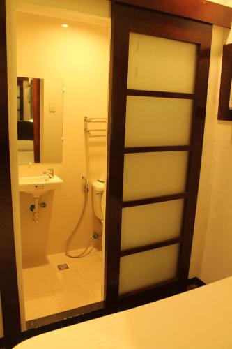 ein Badezimmer mit einem WC, einem Waschbecken und einem Spiegel in der Unterkunft Espineli's in Balayan