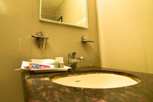 a bathroom counter with a sink and a mirror at MY Bizz Hotel Sapna in Pune