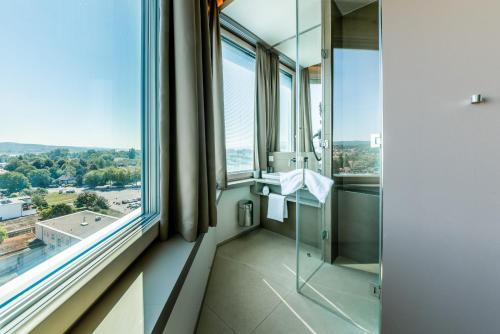 a bathroom with a glass shower stall and a window at aquaTurm Hotel & Energie in Radolfzell am Bodensee