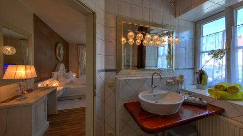 a bathroom with a sink and a mirror and a tub at Boutique Hotel POST ANDECHS in Andechs