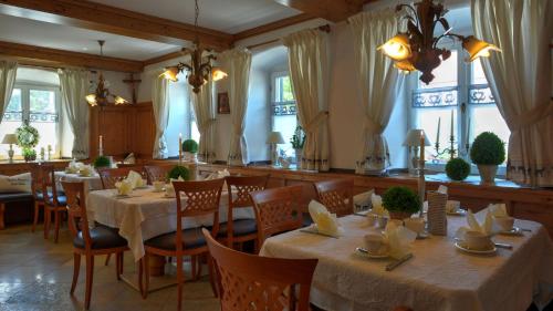 a dining room with tables and chairs and windows at Boutique Hotel POST ANDECHS in Andechs