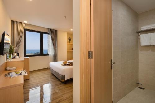 Habitación de hotel con cama y ducha en The Swan Nha Trang Hotel en Nha Trang