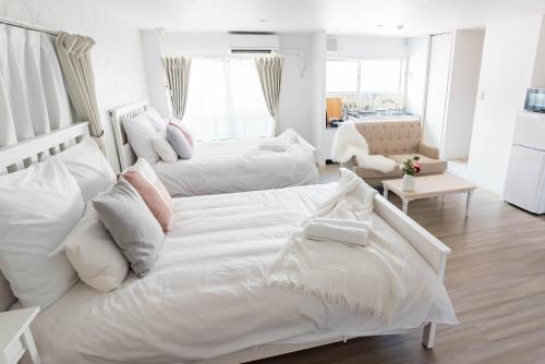 a white bedroom with two beds and a living room at Bijou Suites Granpia in Osaka