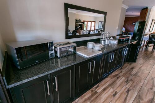 a kitchen with a counter with a microwave and a mirror at Royl Court Guesthouse in Kimberley