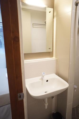 een badkamer met een witte wastafel en een spiegel bij The Center Suites in Cebu City