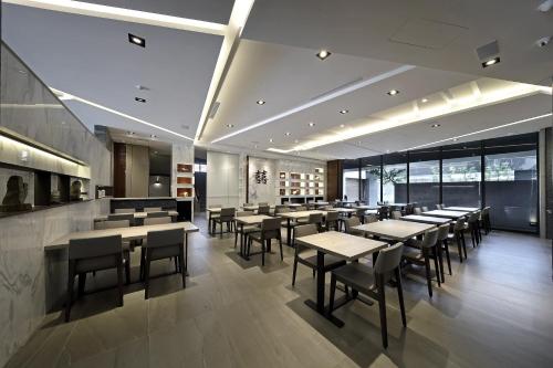 a restaurant with tables and chairs in a room at 正巧文旅 蔬食友善旅館 in Caotun