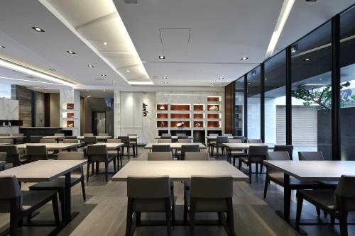 un restaurante con mesas, sillas y ventanas en 正巧文旅 蔬食友善旅館 en Caotun