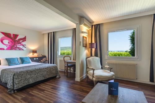 a hotel room with a bed and a chair and a window at Kyriad Prestige Beaune le Panorama in Beaune