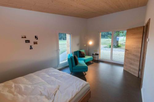 een slaapkamer met een bed, een stoel en ramen bij Au Chant du Vent in Tramelan