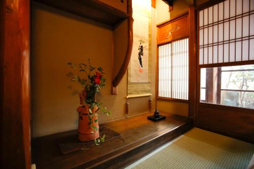 Una habitación con un jarrón con flores. en Matsuharu ANN, en Kioto