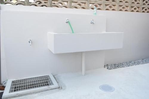uma casa de banho branca com um lavatório e um ralo em Hotel 385 em Ilhas Miyako